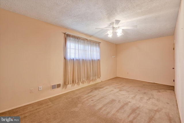 empty room featuring a ceiling fan, visible vents, carpet floors, and a textured ceiling