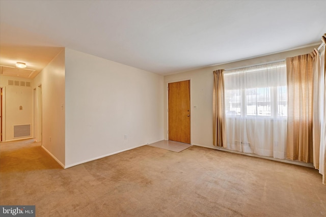 carpeted spare room with attic access and visible vents