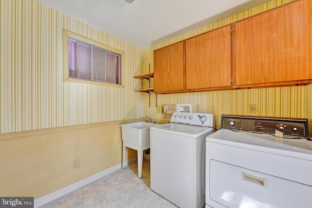 clothes washing area with wallpapered walls, cabinet space, and washing machine and clothes dryer