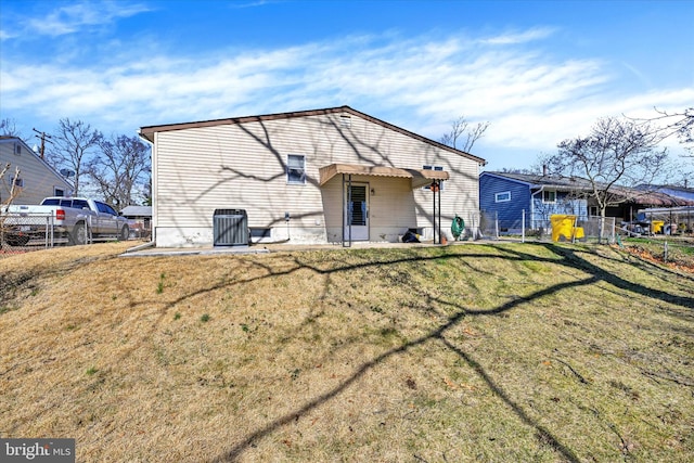 rear view of house with fence and a lawn