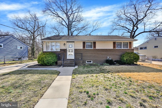 view of front of property with brick siding, a front lawn, and fence