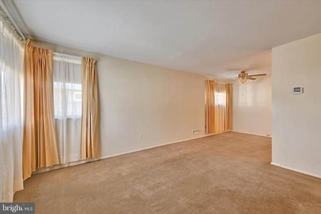 unfurnished room featuring carpet flooring, a ceiling fan, baseboards, and a wealth of natural light