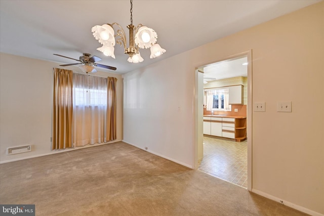 unfurnished room with light carpet, visible vents, ceiling fan with notable chandelier, and baseboards