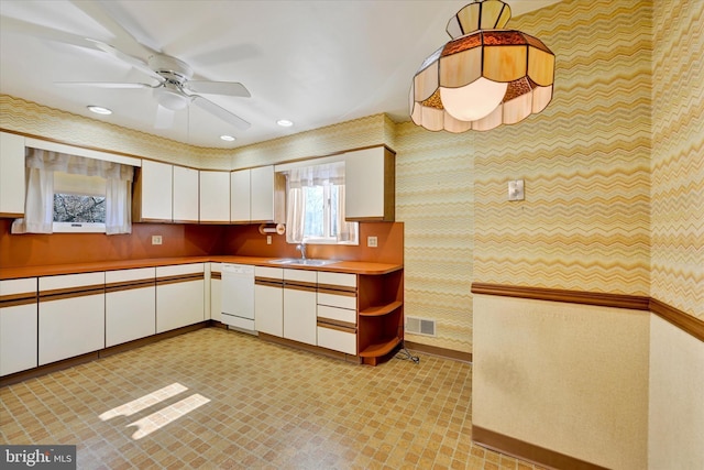 kitchen with visible vents, dishwasher, light countertops, white cabinets, and a sink