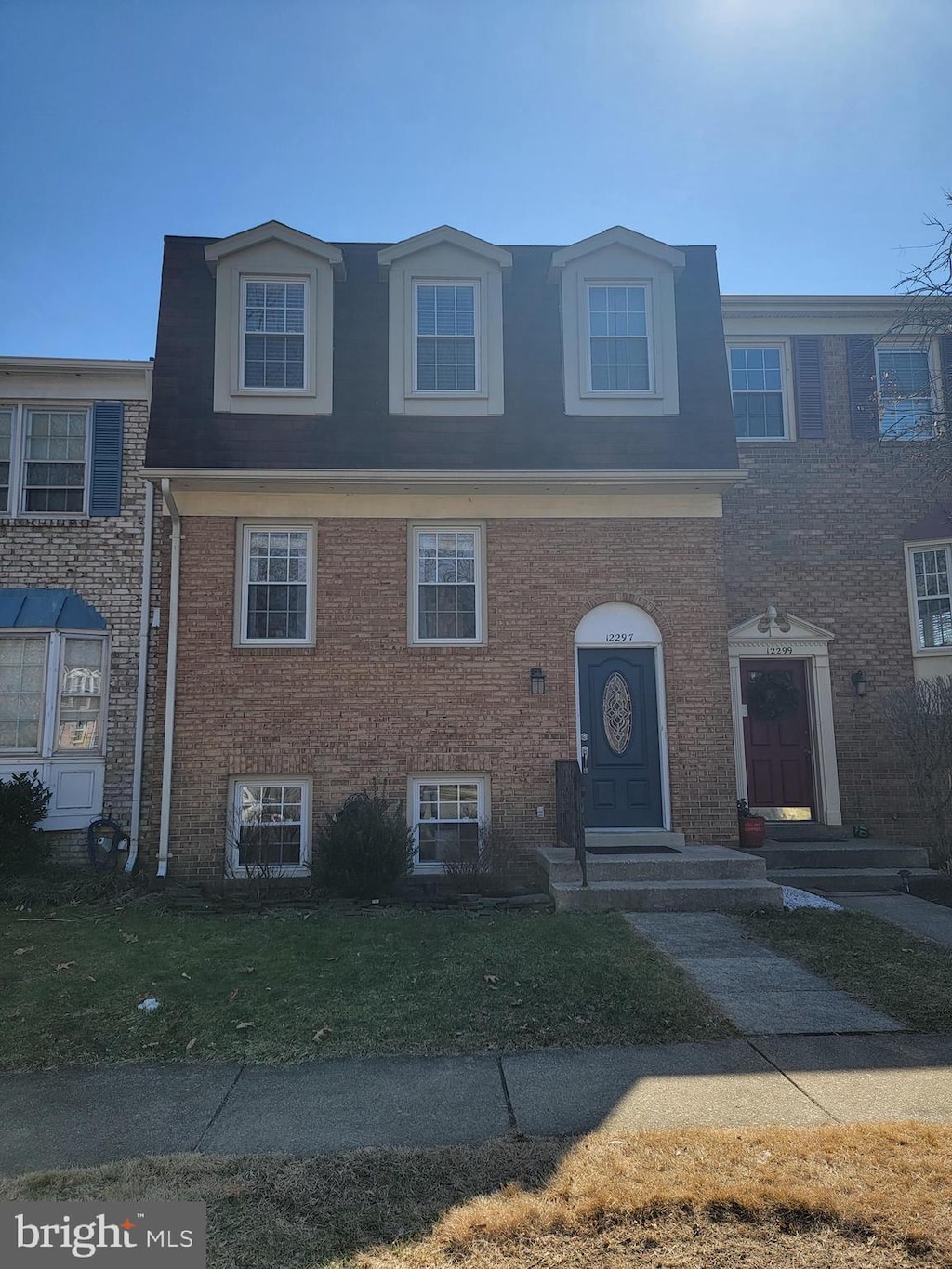 multi unit property featuring a front lawn and brick siding