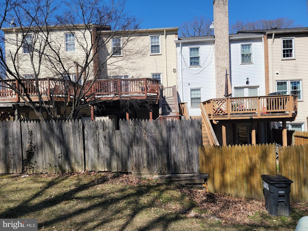 rear view of property with fence, a chimney, and a wooden deck