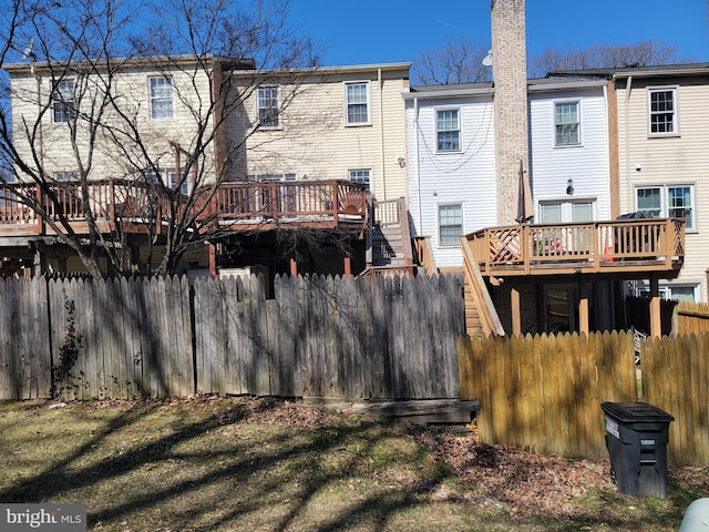 rear view of property with fence, a chimney, and a wooden deck