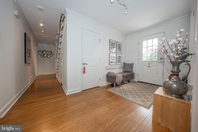 foyer with baseboards, ornamental molding, track lighting, and light wood finished floors