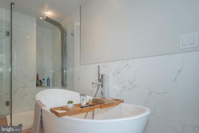 bathroom featuring a marble finish shower, a soaking tub, and tile walls