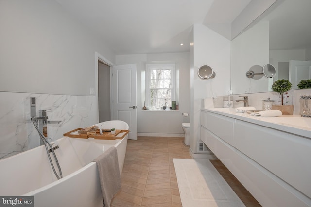 full bath with double vanity, toilet, a soaking tub, and a sink