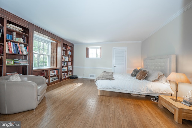 bedroom featuring crown molding, wood finished floors, visible vents, and baseboards