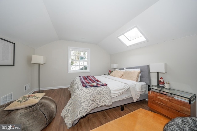 bedroom with lofted ceiling with skylight, visible vents, baseboards, and wood finished floors