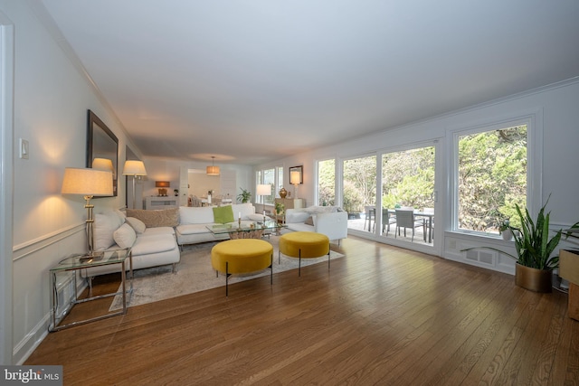 living room with hardwood / wood-style floors, a decorative wall, ornamental molding, and wainscoting