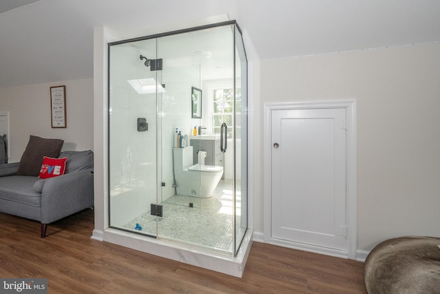 bathroom featuring a shower stall, wood finished floors, and lofted ceiling