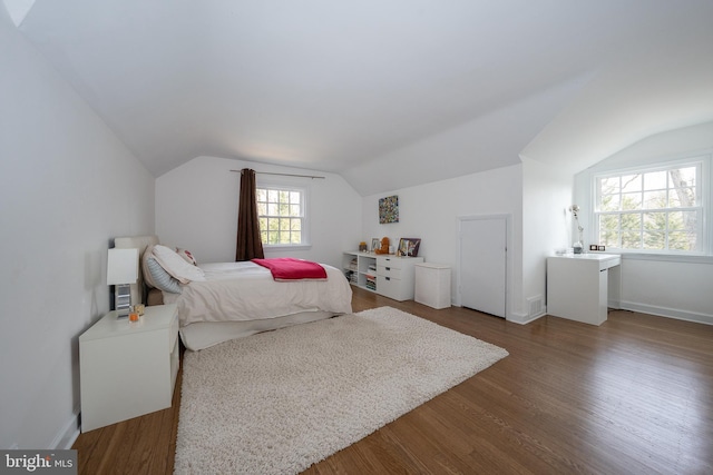 bedroom with baseboards, dark wood-type flooring, and lofted ceiling