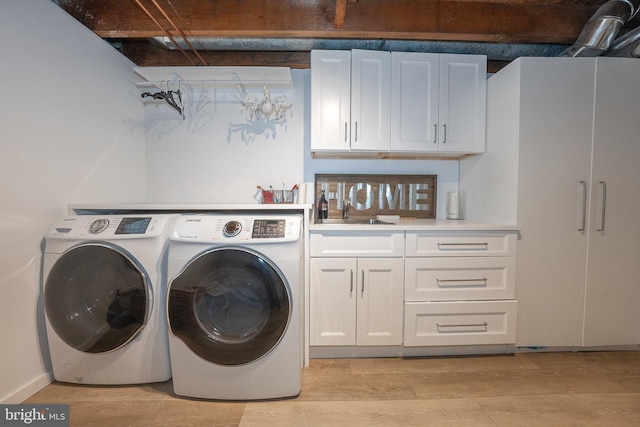 washroom featuring light wood finished floors, cabinet space, washer and dryer, and a sink