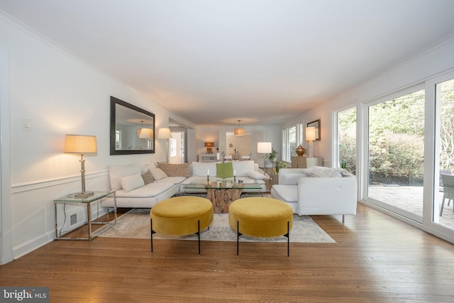 living room with hardwood / wood-style flooring, a decorative wall, a wainscoted wall, and ornamental molding