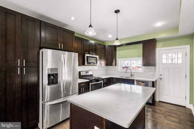 kitchen featuring backsplash, dark brown cabinetry, appliances with stainless steel finishes, dark wood-style floors, and a sink