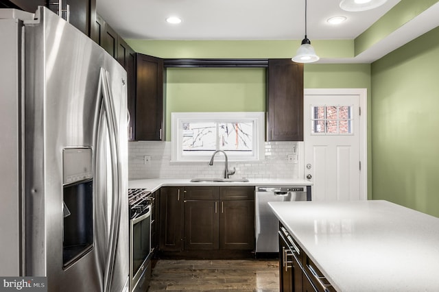 kitchen with a sink, stainless steel appliances, dark brown cabinetry, and a healthy amount of sunlight