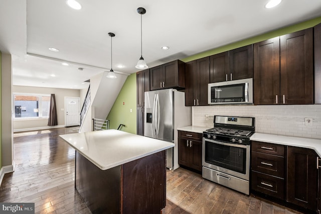 kitchen with backsplash, dark brown cabinetry, light countertops, dark wood-style floors, and stainless steel appliances