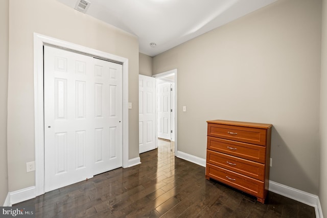 bedroom with dark wood finished floors, baseboards, visible vents, and a closet