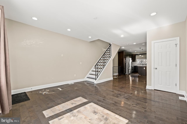 unfurnished living room featuring recessed lighting, stairway, baseboards, and dark wood-style floors