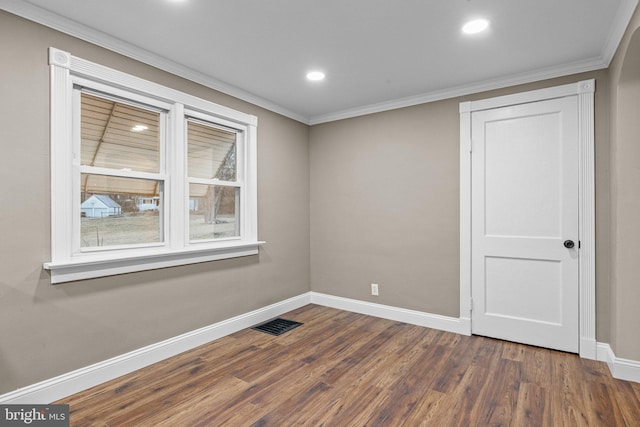 spare room with dark wood-style floors, visible vents, crown molding, and baseboards