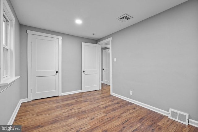 unfurnished bedroom with wood finished floors, visible vents, and baseboards