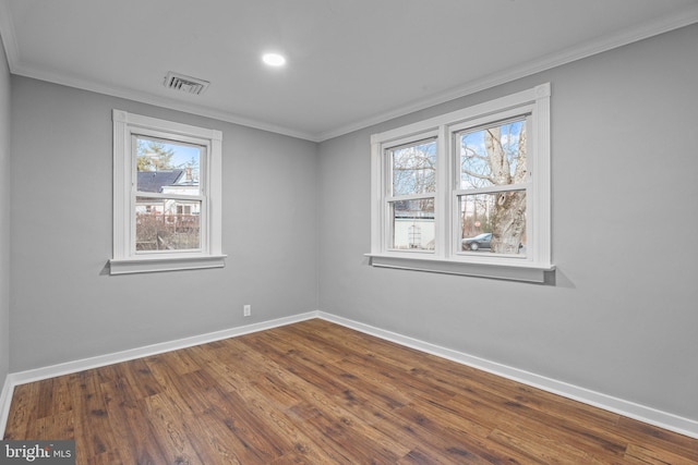 spare room featuring visible vents, baseboards, dark wood-style flooring, and crown molding