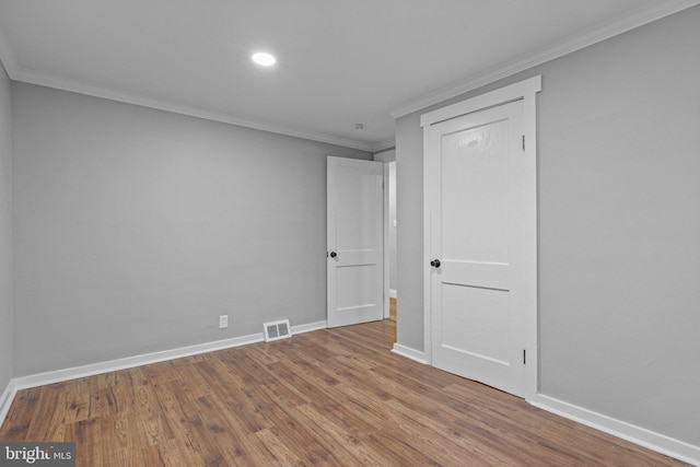 unfurnished room featuring visible vents, baseboards, wood finished floors, and crown molding