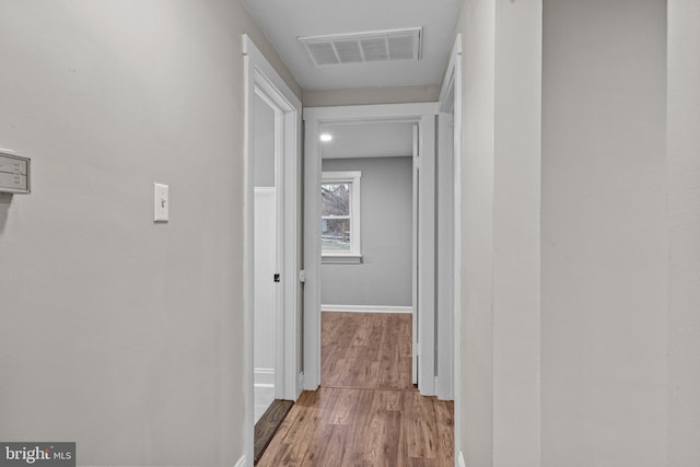 corridor with wood finished floors, visible vents, and baseboards