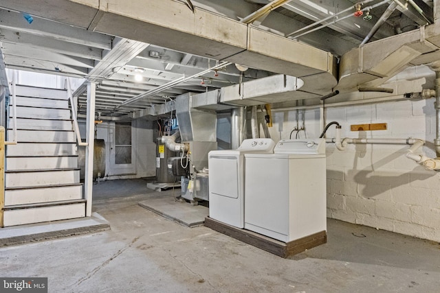 unfinished basement with heating fuel, heating unit, washing machine and dryer, stairway, and concrete block wall