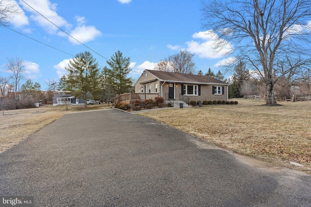 view of front of home with aphalt driveway, covered porch, and a front lawn