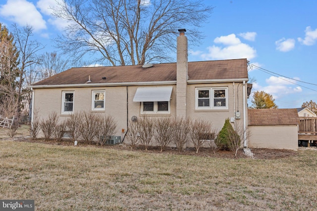 rear view of property featuring a lawn, cooling unit, a chimney, and roof with shingles