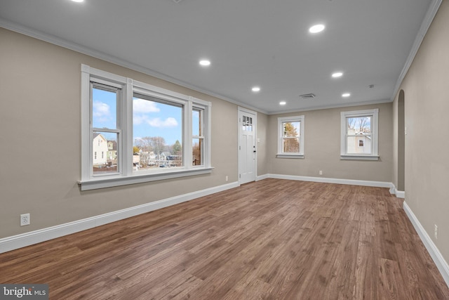 spare room featuring wood finished floors, recessed lighting, arched walkways, crown molding, and baseboards