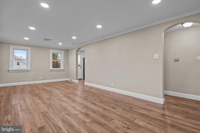 empty room with baseboards, arched walkways, and ornamental molding