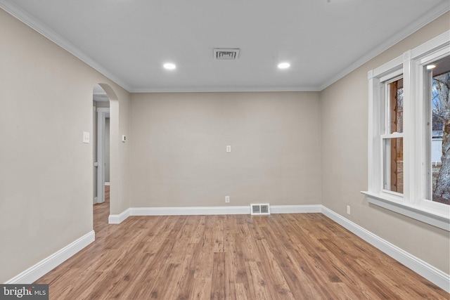 unfurnished room with arched walkways, visible vents, baseboards, and wood finished floors