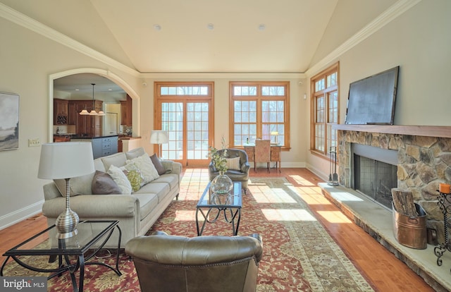 living area featuring lofted ceiling, light wood-style flooring, arched walkways, and a wealth of natural light