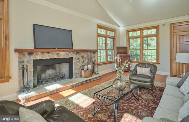 living area featuring crown molding, baseboards, vaulted ceiling, a stone fireplace, and wood finished floors