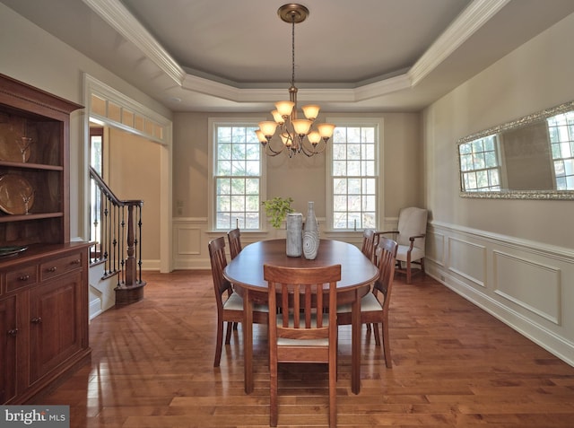 dining space featuring a tray ceiling, an inviting chandelier, wood finished floors, and stairs