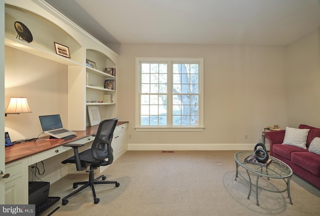 office area featuring built in features, baseboards, and light colored carpet