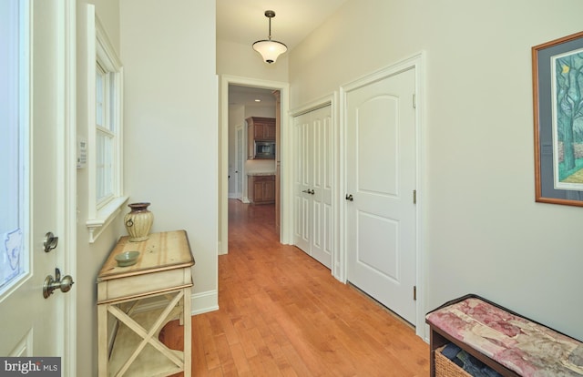 corridor with light wood-type flooring and baseboards