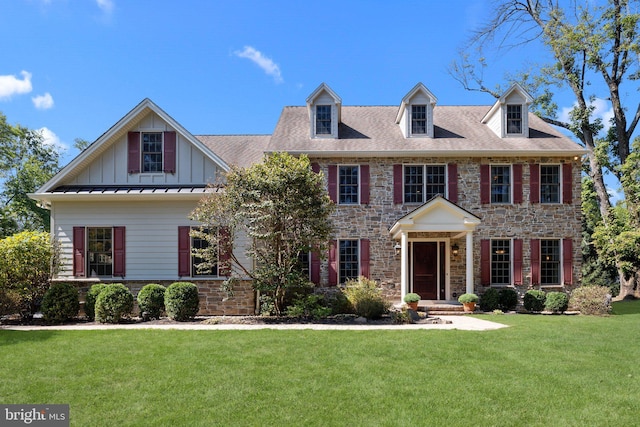 colonial house with stone siding, board and batten siding, a front yard, and a standing seam roof