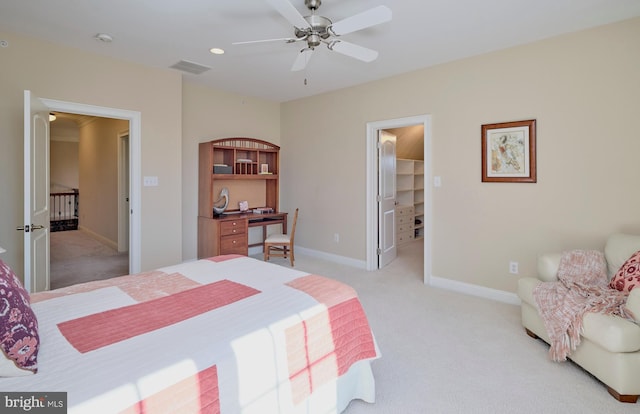 bedroom featuring a spacious closet, visible vents, baseboards, ceiling fan, and light colored carpet