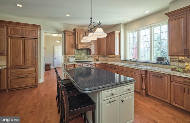 kitchen with a breakfast bar area, light wood finished floors, backsplash, and a sink