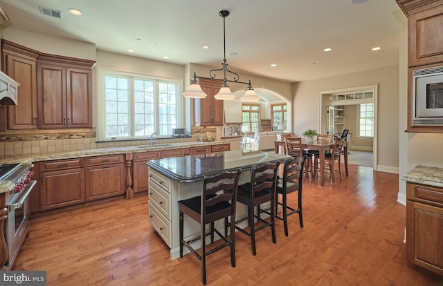 kitchen featuring light wood finished floors, visible vents, backsplash, appliances with stainless steel finishes, and a sink