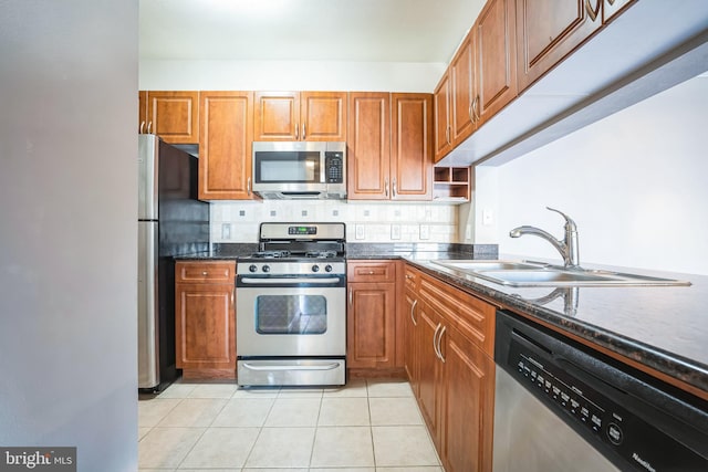 kitchen with light tile patterned floors, brown cabinets, appliances with stainless steel finishes, and a sink