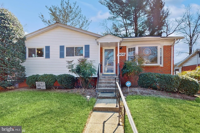 view of front of house featuring brick siding, entry steps, and a front yard