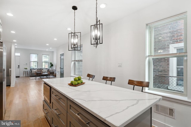 kitchen with light wood finished floors, visible vents, decorative light fixtures, open floor plan, and recessed lighting