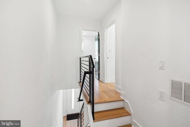 stairs with visible vents, baseboards, and wood finished floors